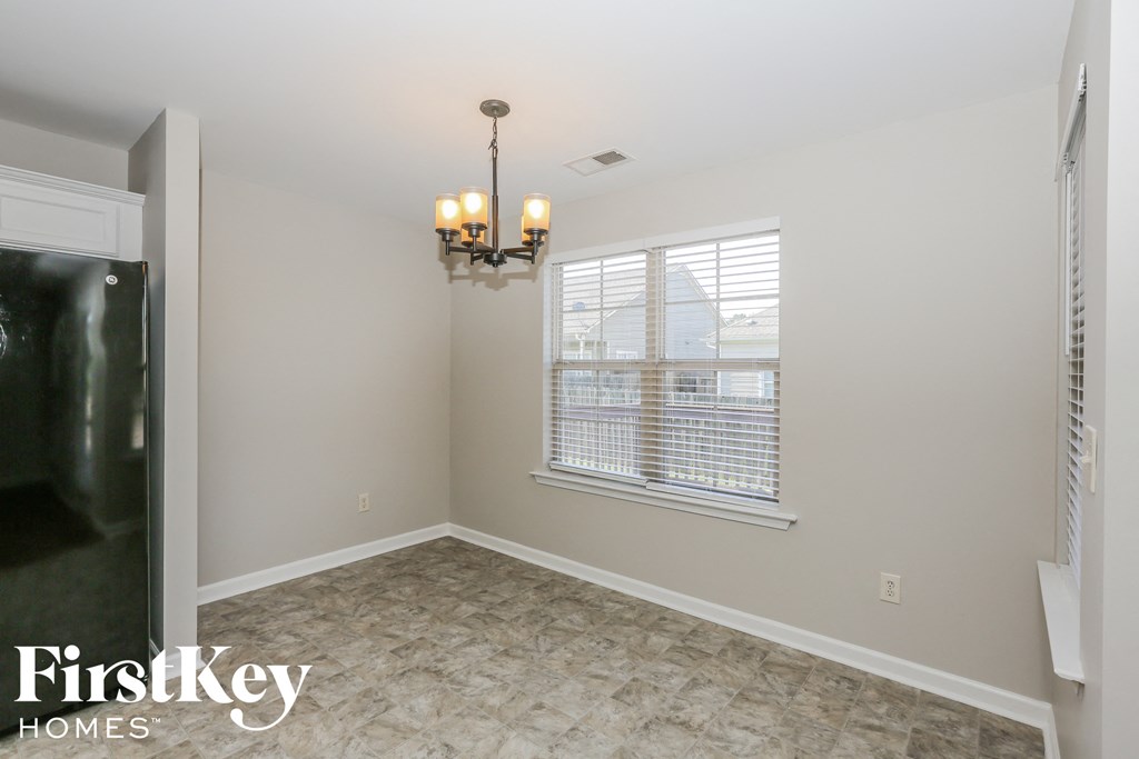 an empty dining room with a chandelier and a window
