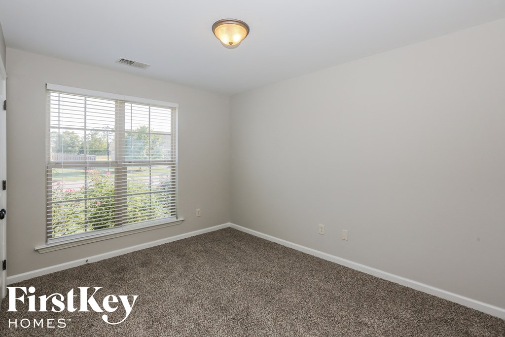 the upstairs bedroom has a carpeted floor and a large window