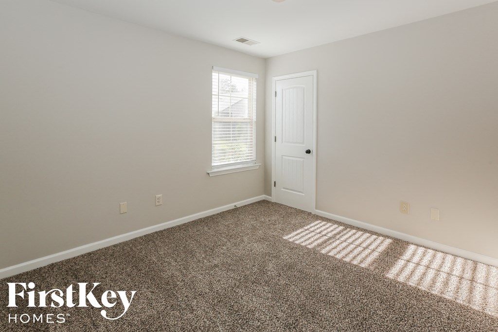 a bedroom with a carpeted floor and a white door