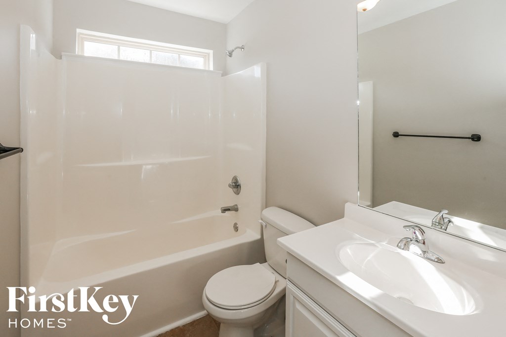 a white bathroom with a shower toilet and sink
