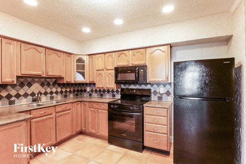 A kitchen with wooden cabinets and black appliances.