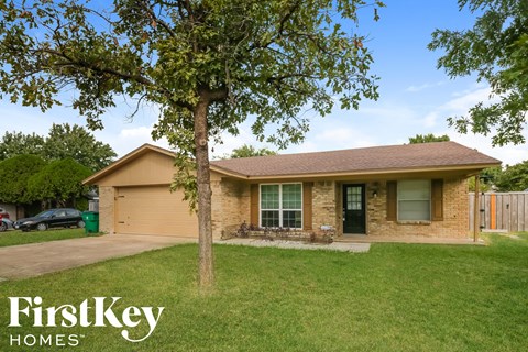 a brown brick house with a tree in the yard
