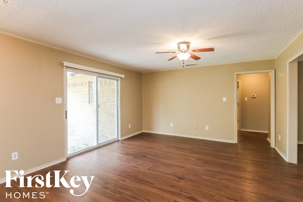 an empty living room with wood floors and a ceiling fan
