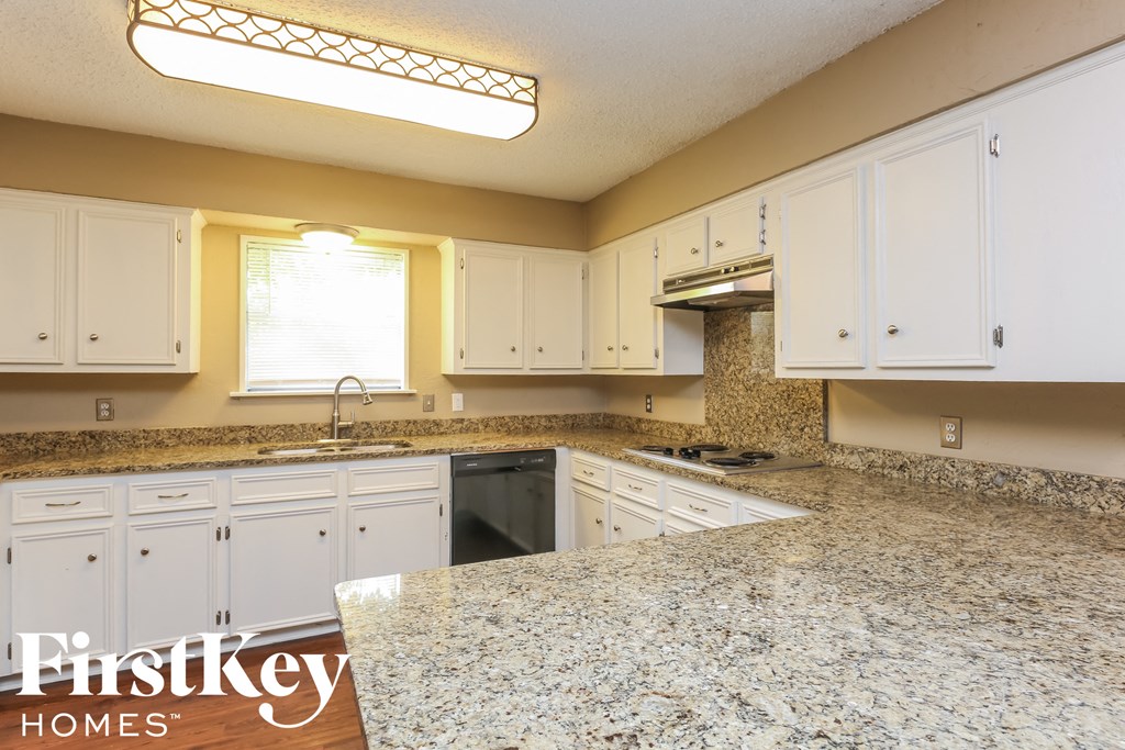 a kitchen with white cabinets and granite counter tops