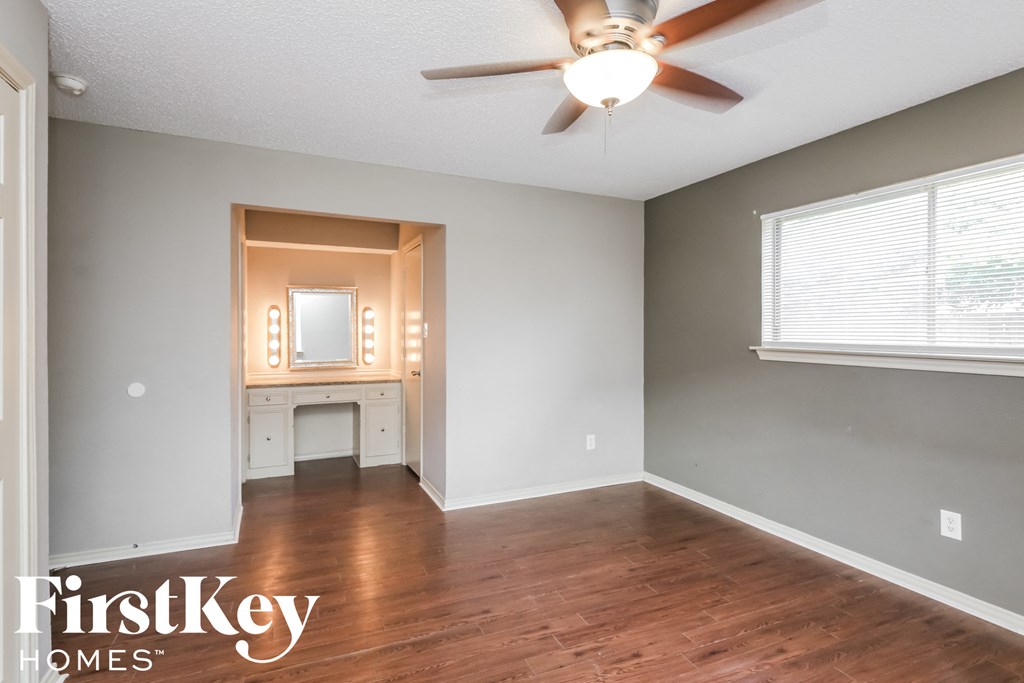 an empty living room with wood floors and a ceiling fan