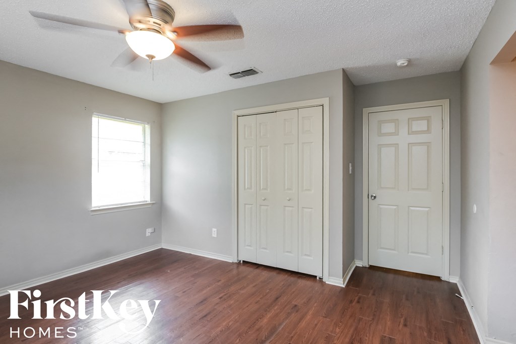 an empty living room with white doors and a ceiling fan