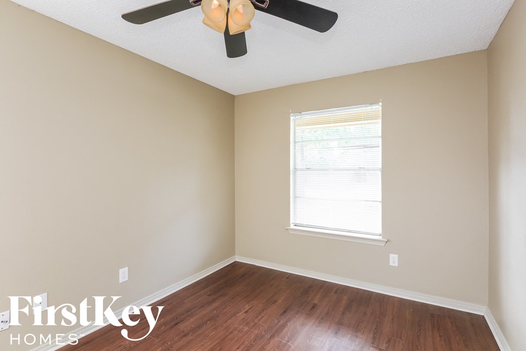 a bedroom with wood floors and a ceiling fan