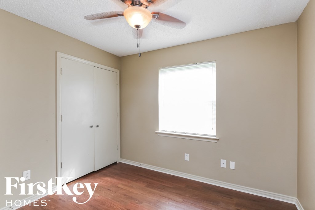 a bedroom with wood flooring and a ceiling fan
