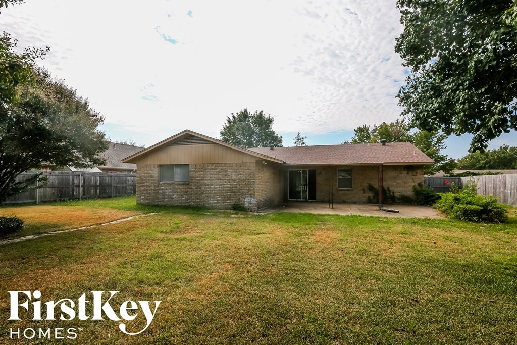 a small brick house with a yard and a fence