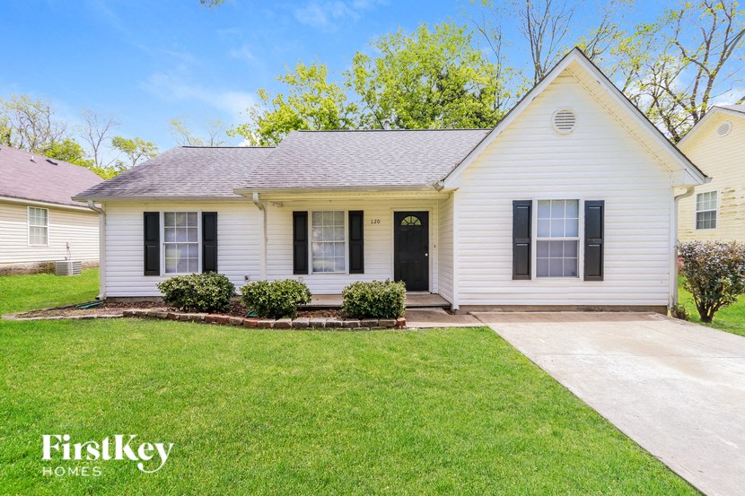 a small white house with black shutters and a lawn