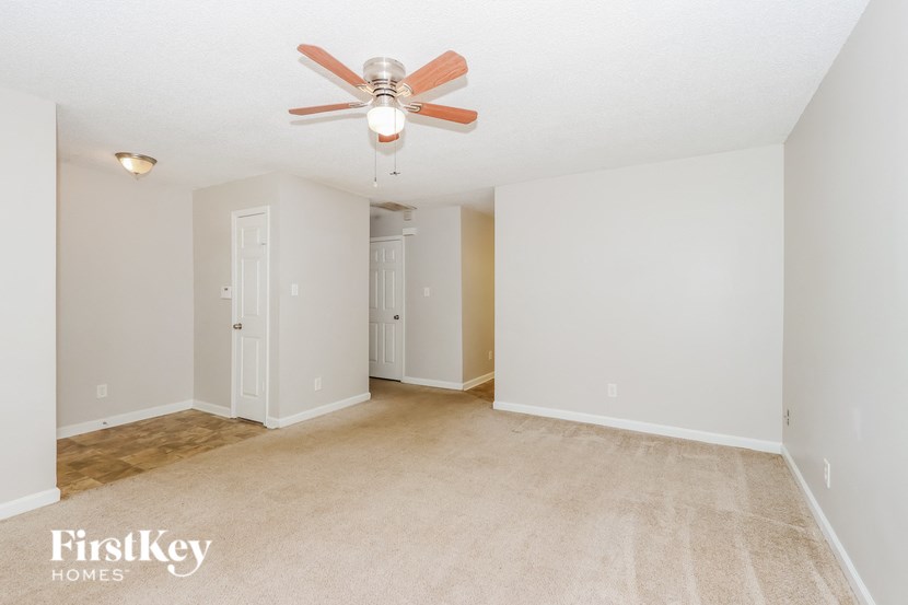 a spacious living room with carpet and a ceiling fan