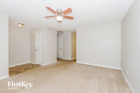 a spacious living room with carpet and a ceiling fan