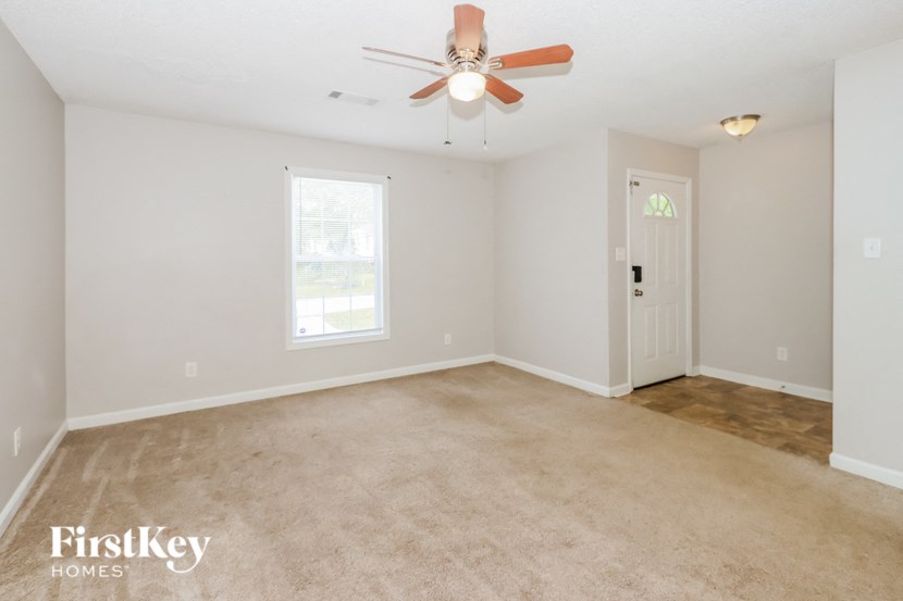 a empty living room with a ceiling fan and a white door