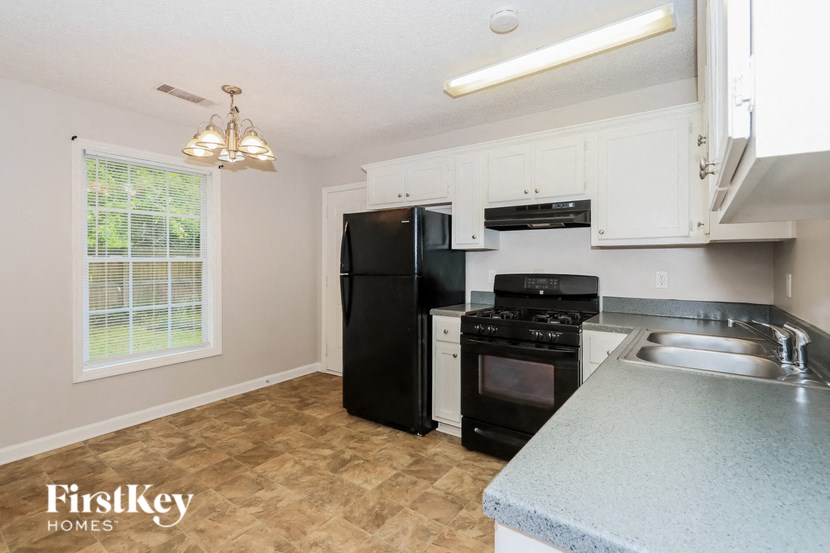 an empty kitchen with black appliances and white cabinets