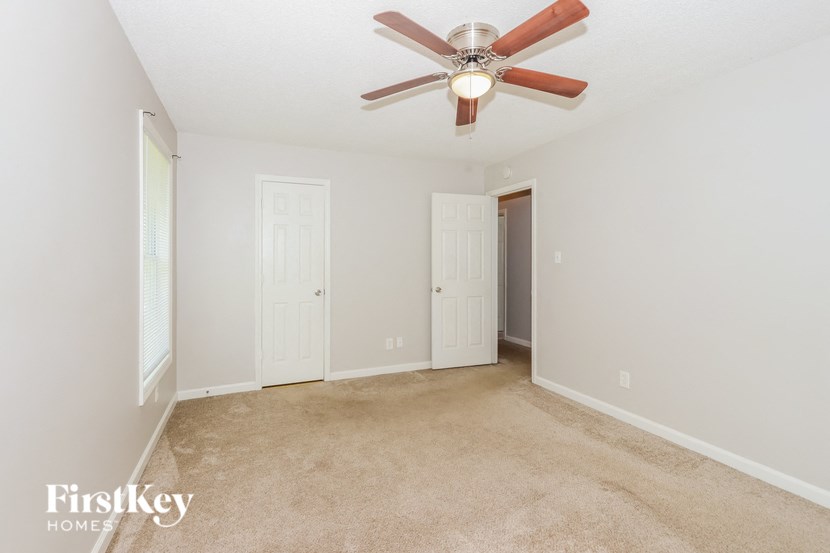 a living room with carpet and a ceiling fan