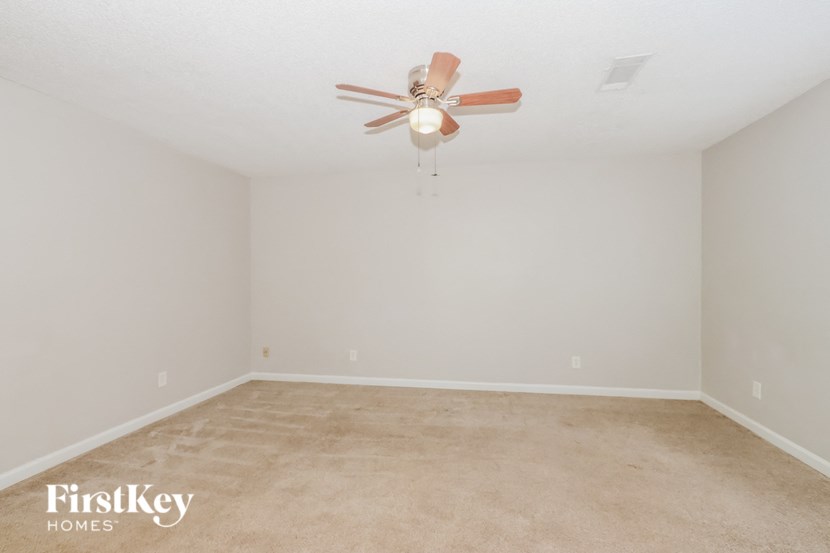 a bedroom with white walls and a ceiling fan