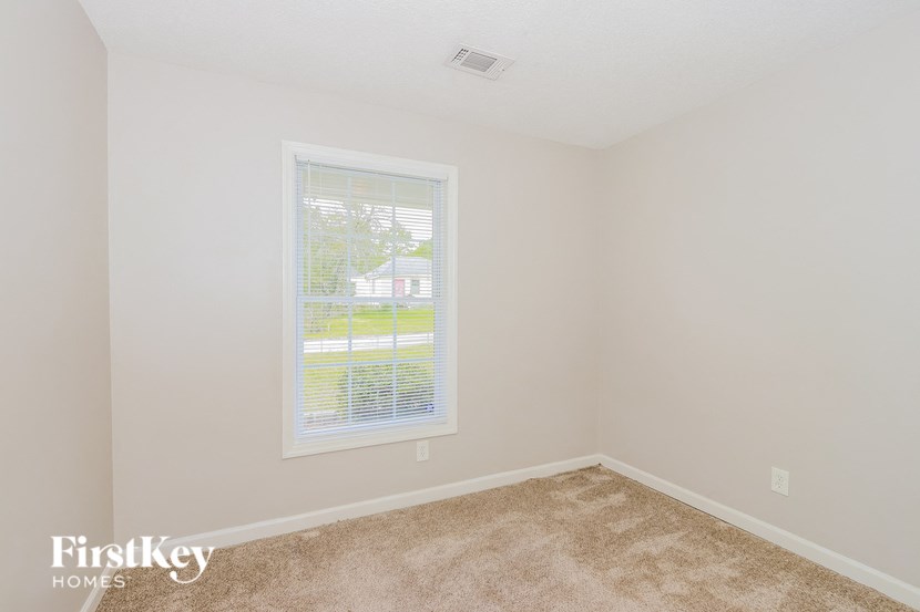 a bedroom with a window and a carpeted floor