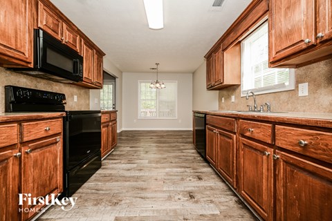 A kitchen with wooden cabinets and a black microwave.