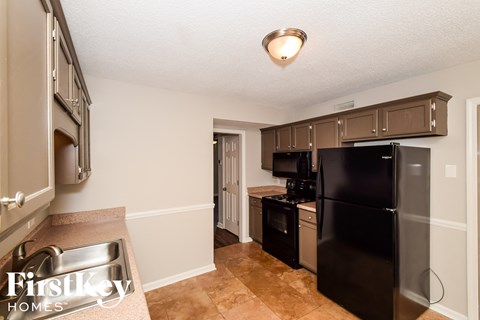 A kitchen with a black refrigerator and a sink.