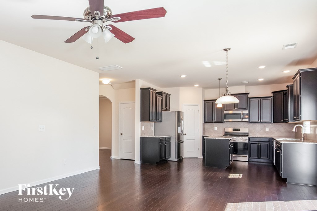 a kitchen with black cabinets and stainless steel appliances and a ceiling fan