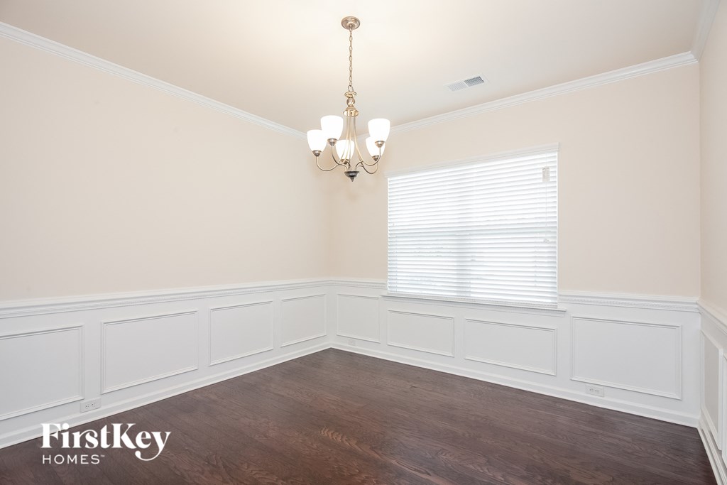 a dining room with white walls and a window and a chandelier