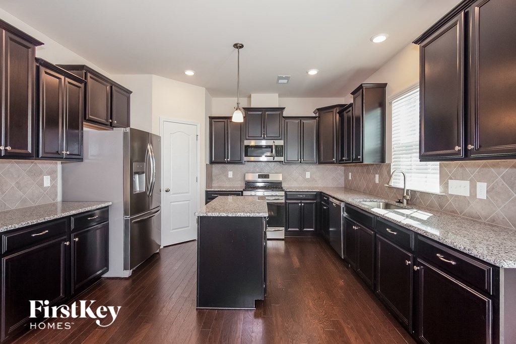 a kitchen with black cabinets and granite counter tops and stainless steel appliances