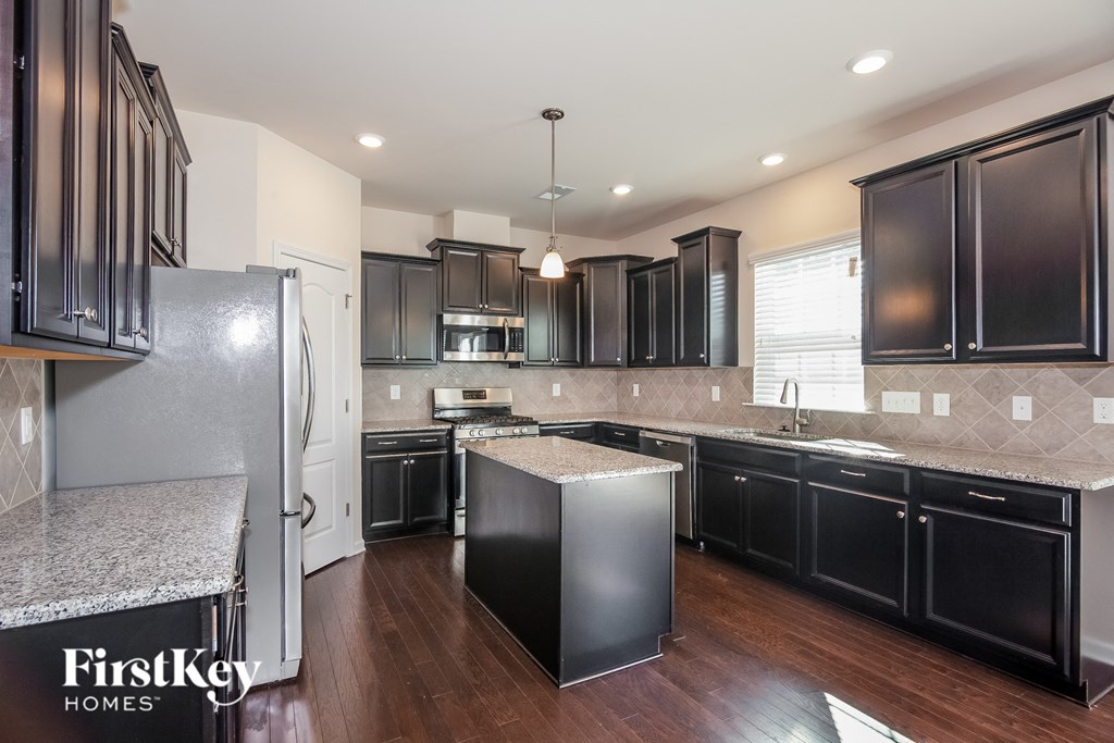 a kitchen with black cabinets and white countertops and stainless steel appliances