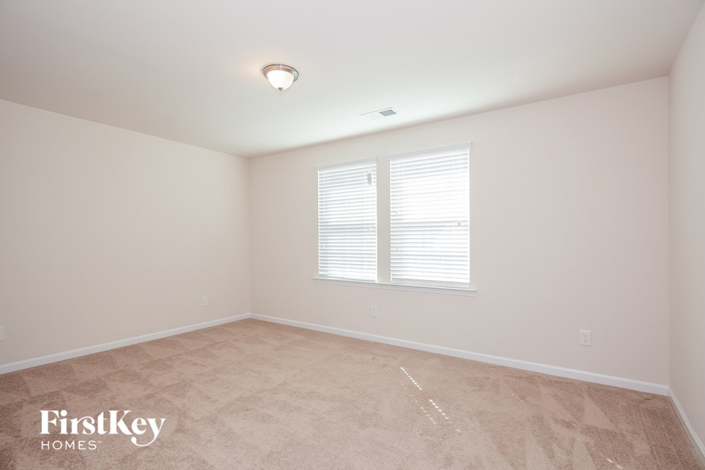 the living room of a home with white walls and a window