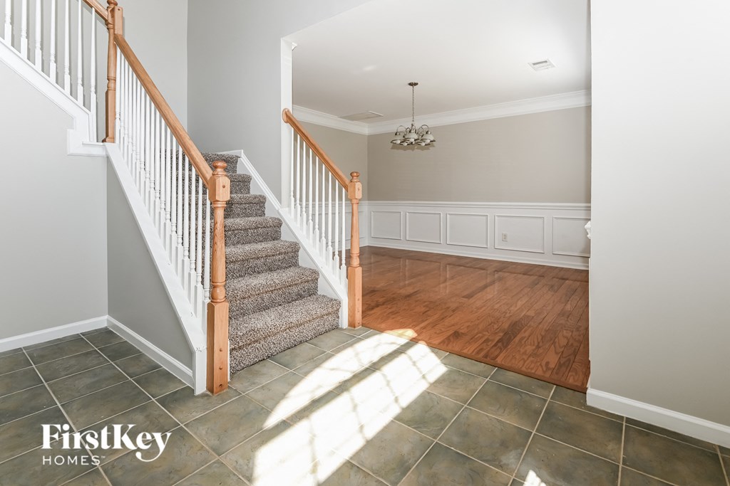 A staircase with a wooden handrail and a chandelier in a room with a wooden floor.