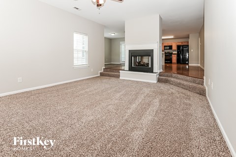 A spacious living room with a fireplace and carpeted floor.