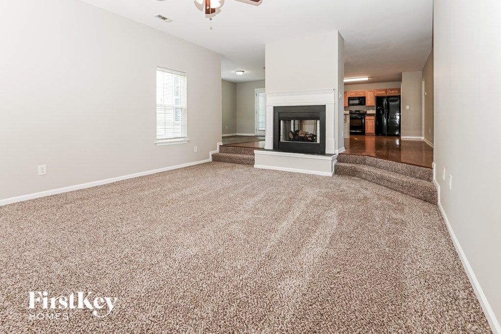 A spacious living room with a fireplace and carpeted floor.