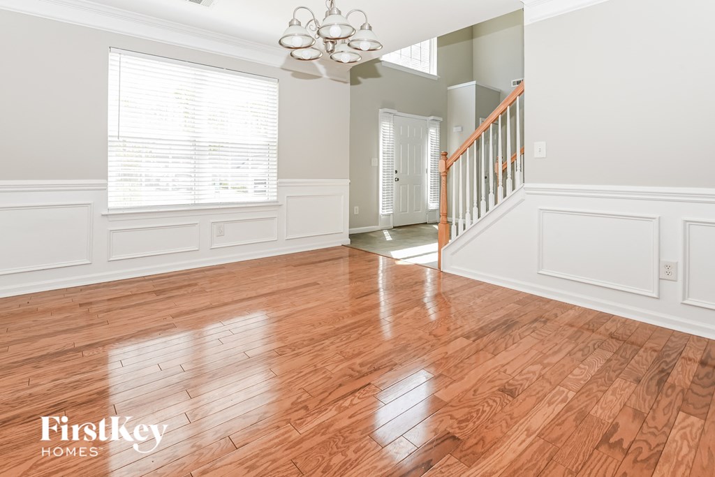 A room with wooden floors and a staircase in the background.