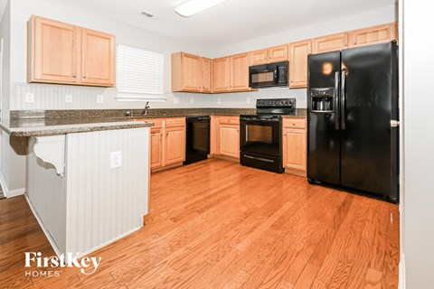 A kitchen with wooden cabinets and a black refrigerator.
