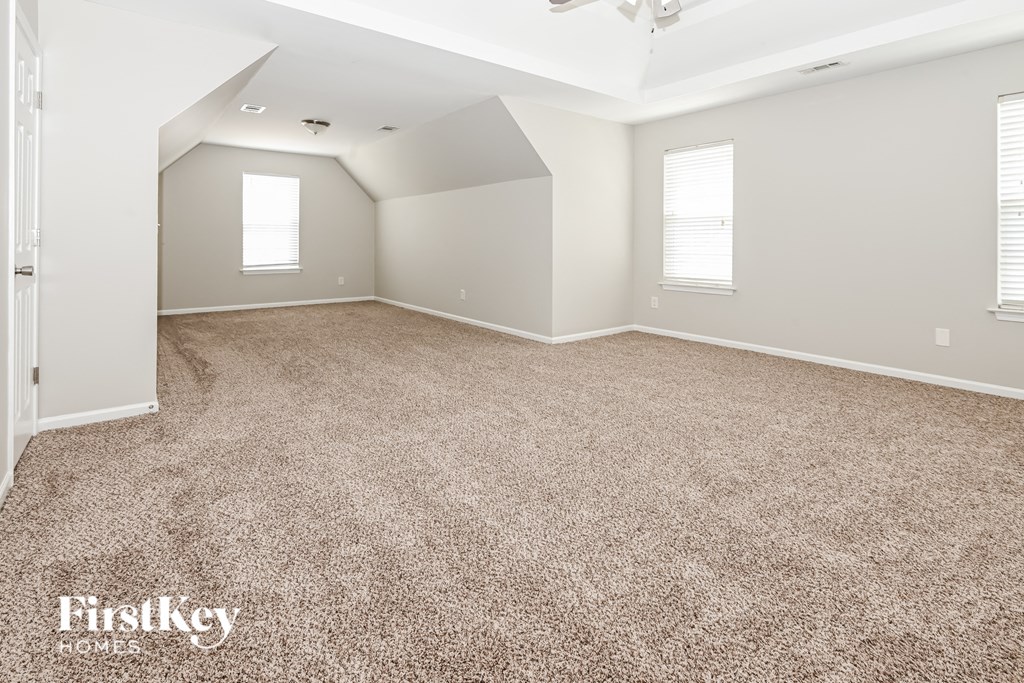 A spacious room with a carpeted floor and a ceiling fan.