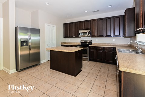 A kitchen with a refrigerator, stove, and sink.