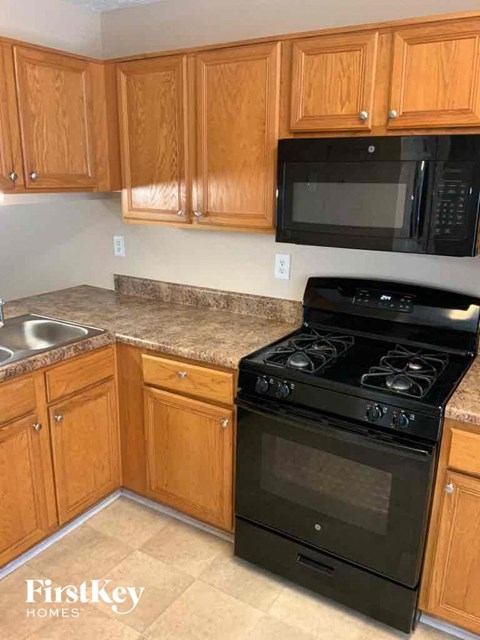 A kitchen with wooden cabinets and a black stove top oven.