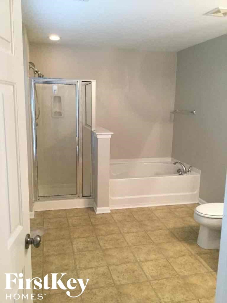 A white bathroom with a walk in shower and toilet.