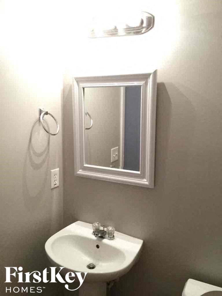 A white sink in a bathroom with a mirror above it.