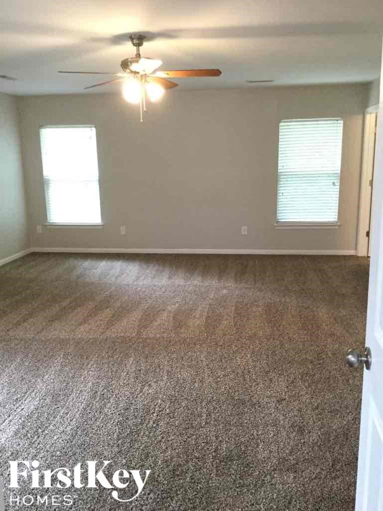 A room with a carpeted floor and a ceiling fan.