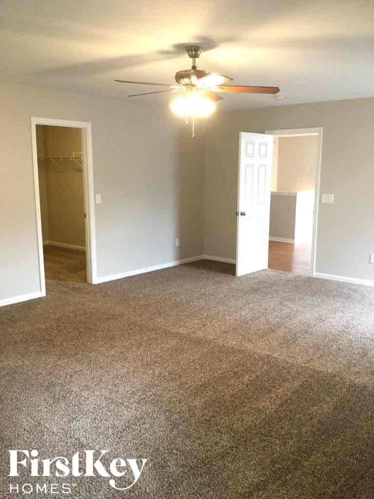 A carpeted room with a ceiling fan and two doors.