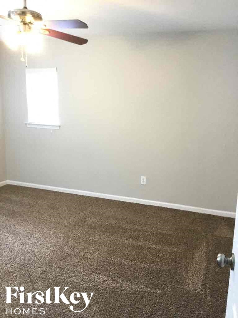 A room with a carpet floor and a ceiling fan.