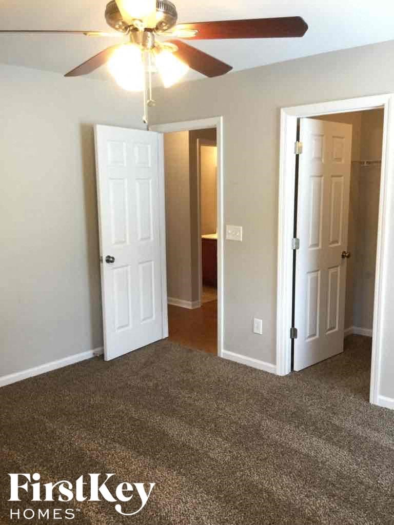 A room with a ceiling fan and two doors, one of which is open.