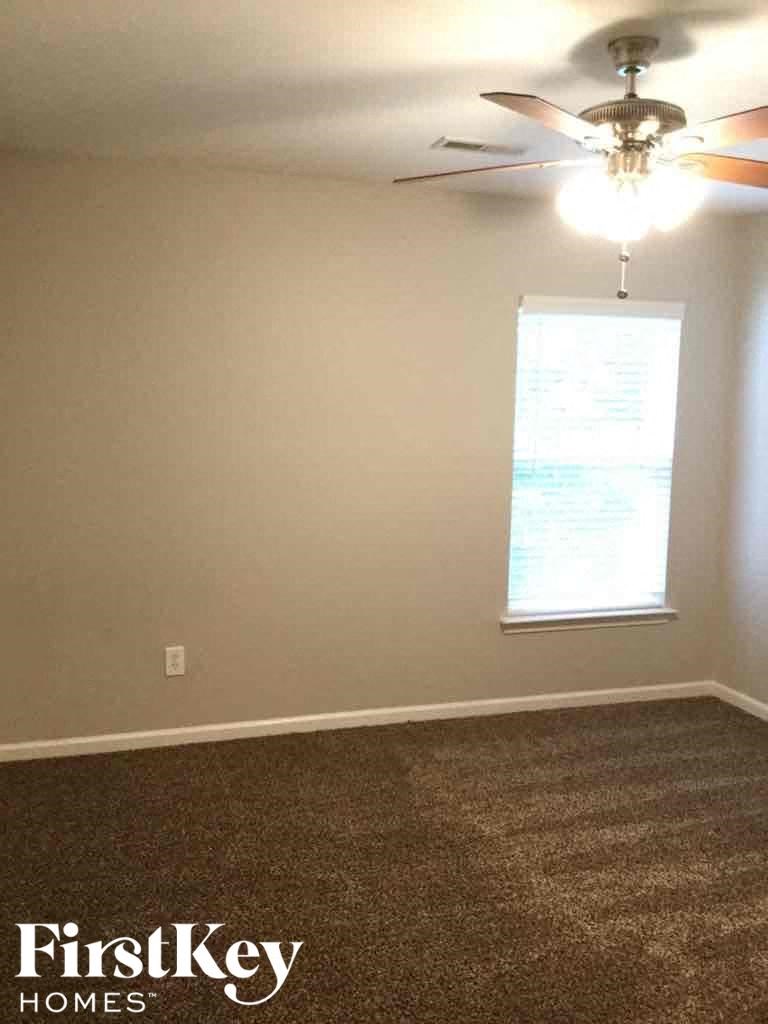A room with a ceiling fan and a window with blinds.