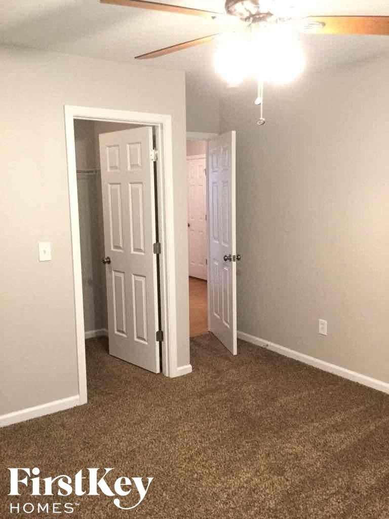 A room with a carpeted floor and a ceiling fan.