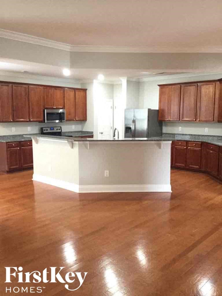 A kitchen with wooden cabinets and a black fridge.