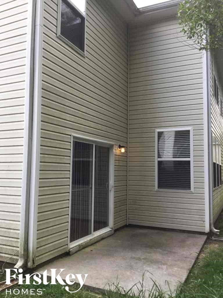 A small balcony with a sliding door and a window is on the side of a house.