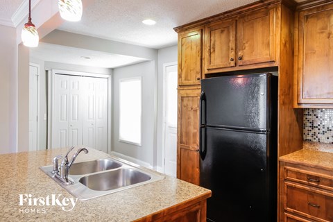 A kitchen with wooden cabinets and a black refrigerator.