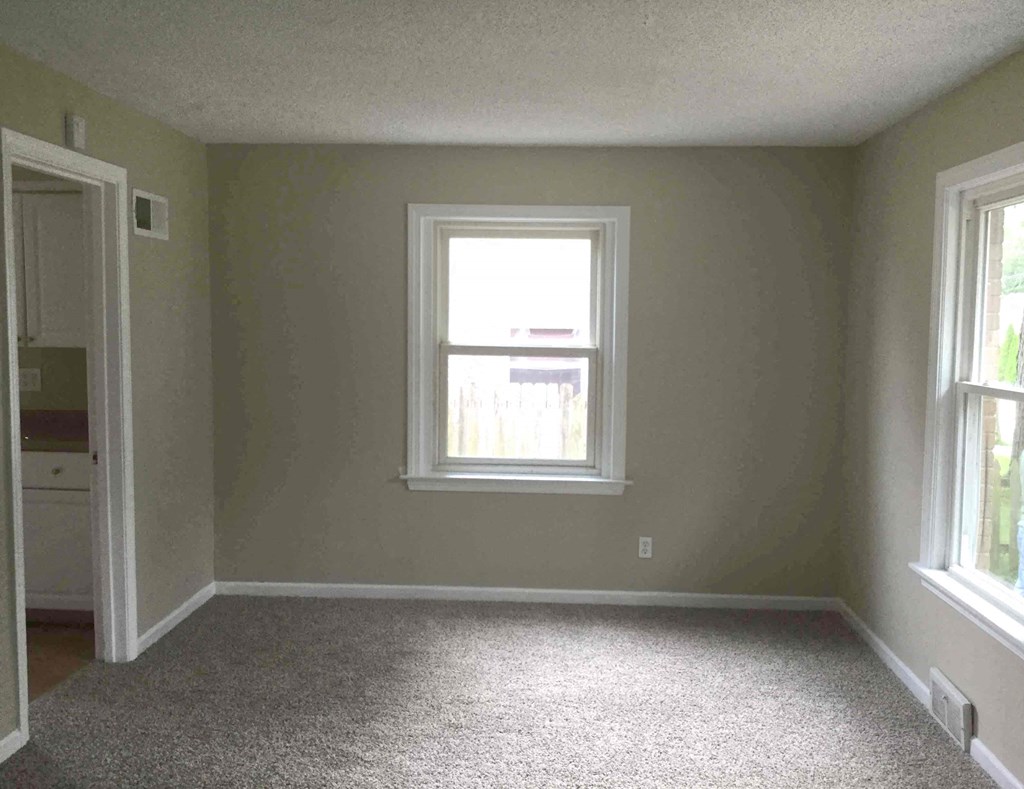 A room with a carpeted floor and a window.