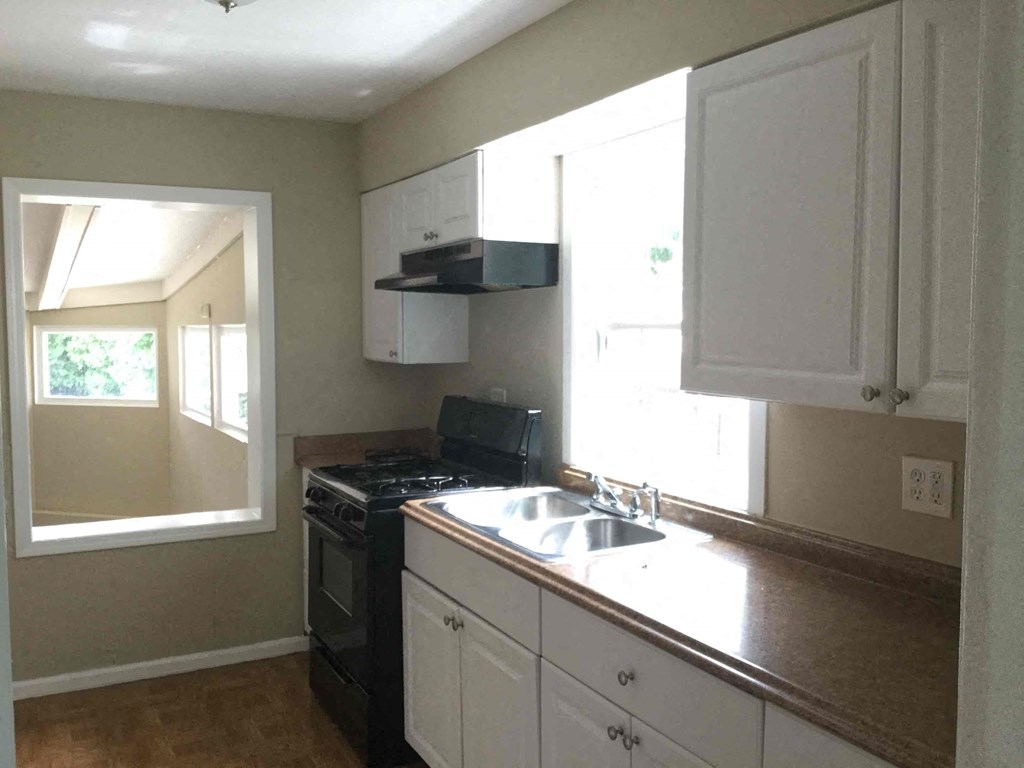 A kitchen with white cabinets and a black stove top oven.