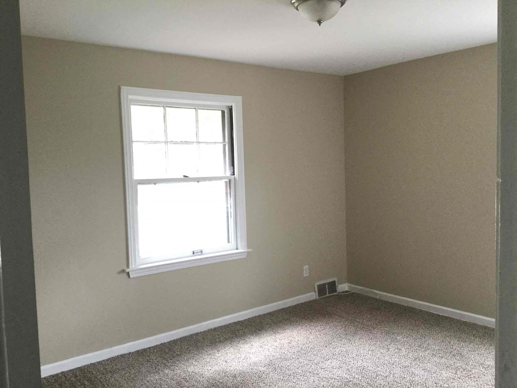 A room with a window and carpeted floor.